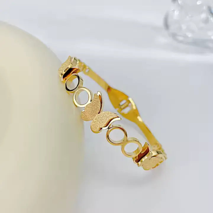 Gold bracelet with butterfly design on a light background