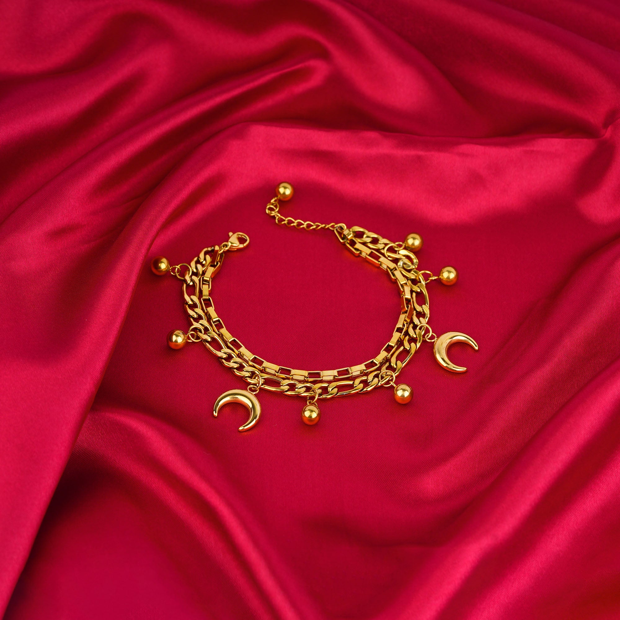 Gold bracelet with charms on a red satin background