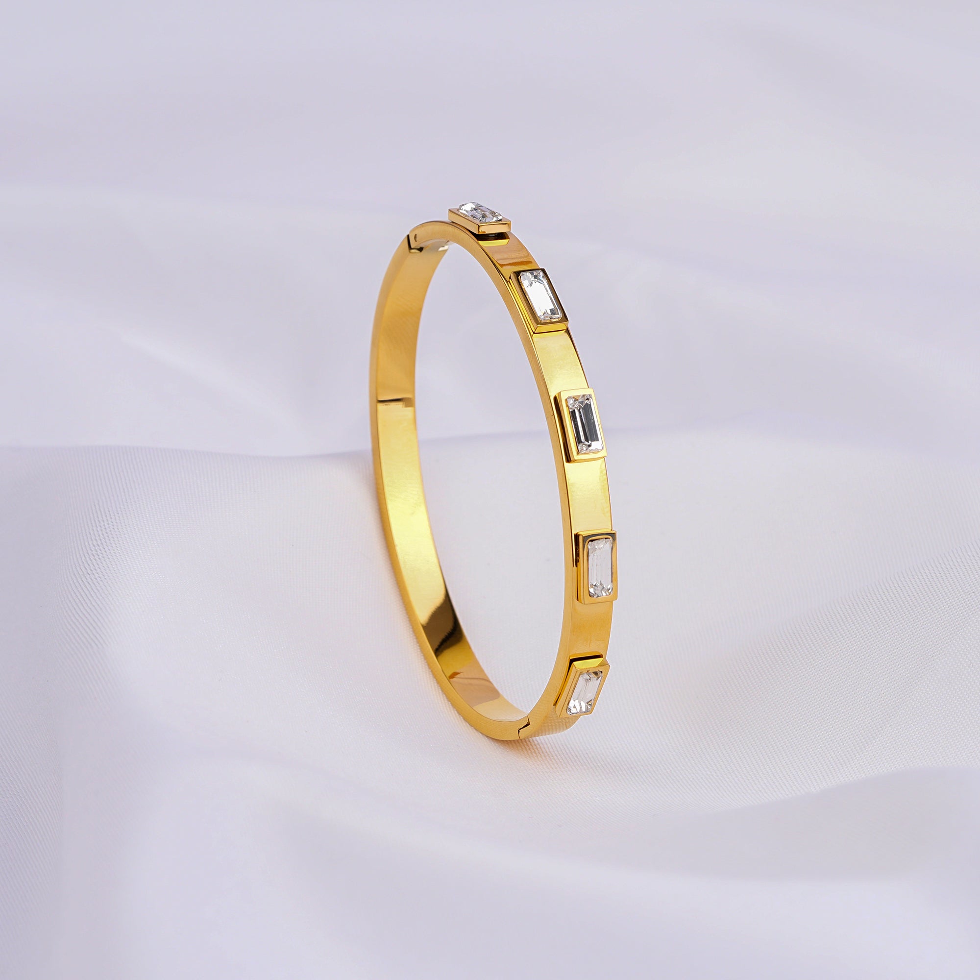 Gold bracelet with embedded stones on a light gray background