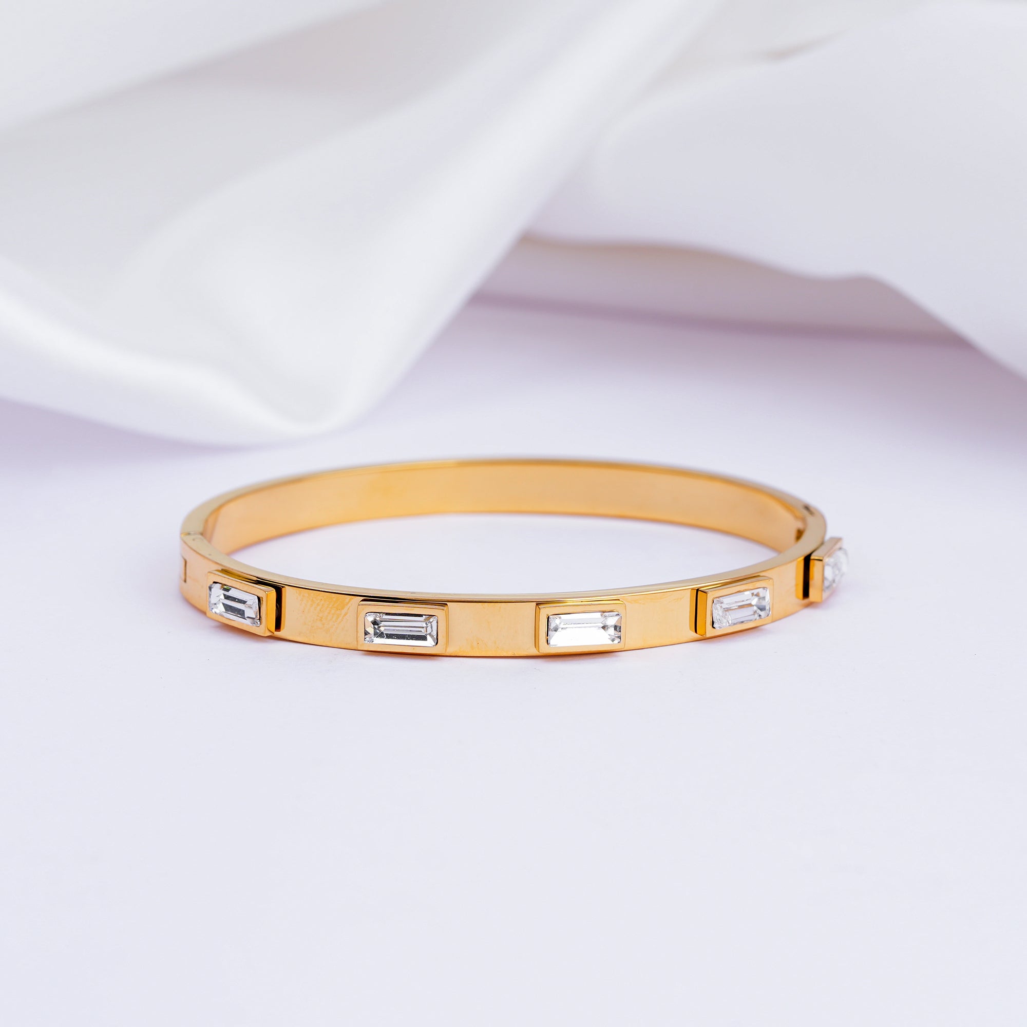 Gold bracelet with embedded crystals on a light fabric background