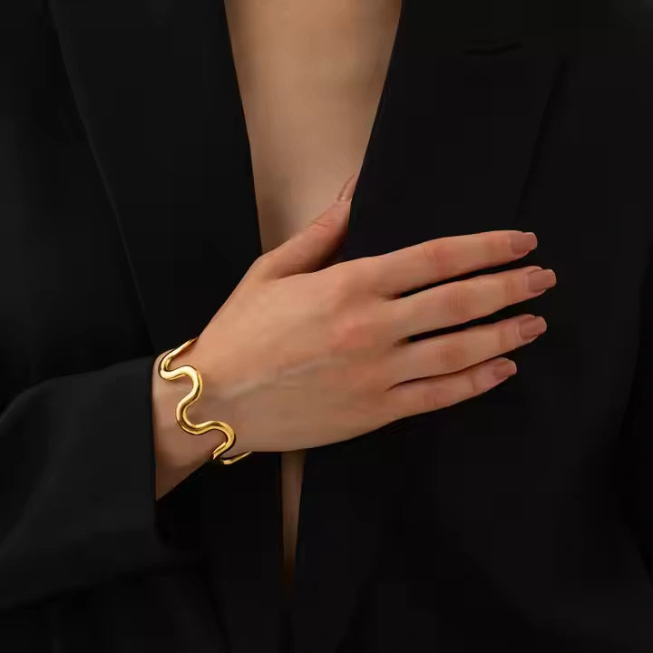 Gold bracelet on a hand against a black background