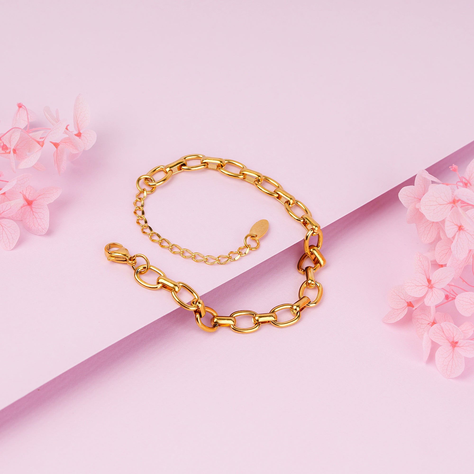 Gold chain bracelet on a pink background with floral elements