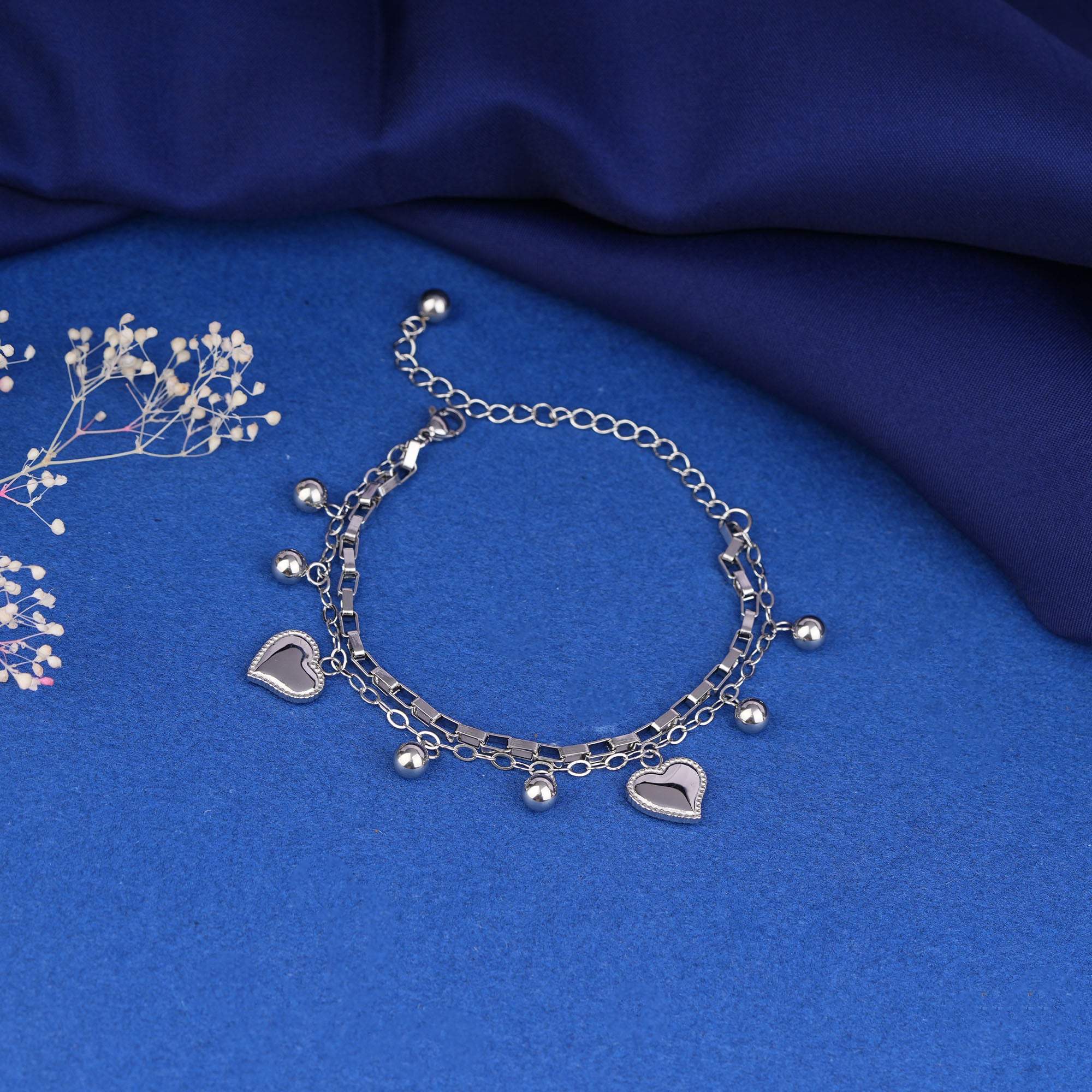 Silver bracelet with heart charms on a blue fabric background