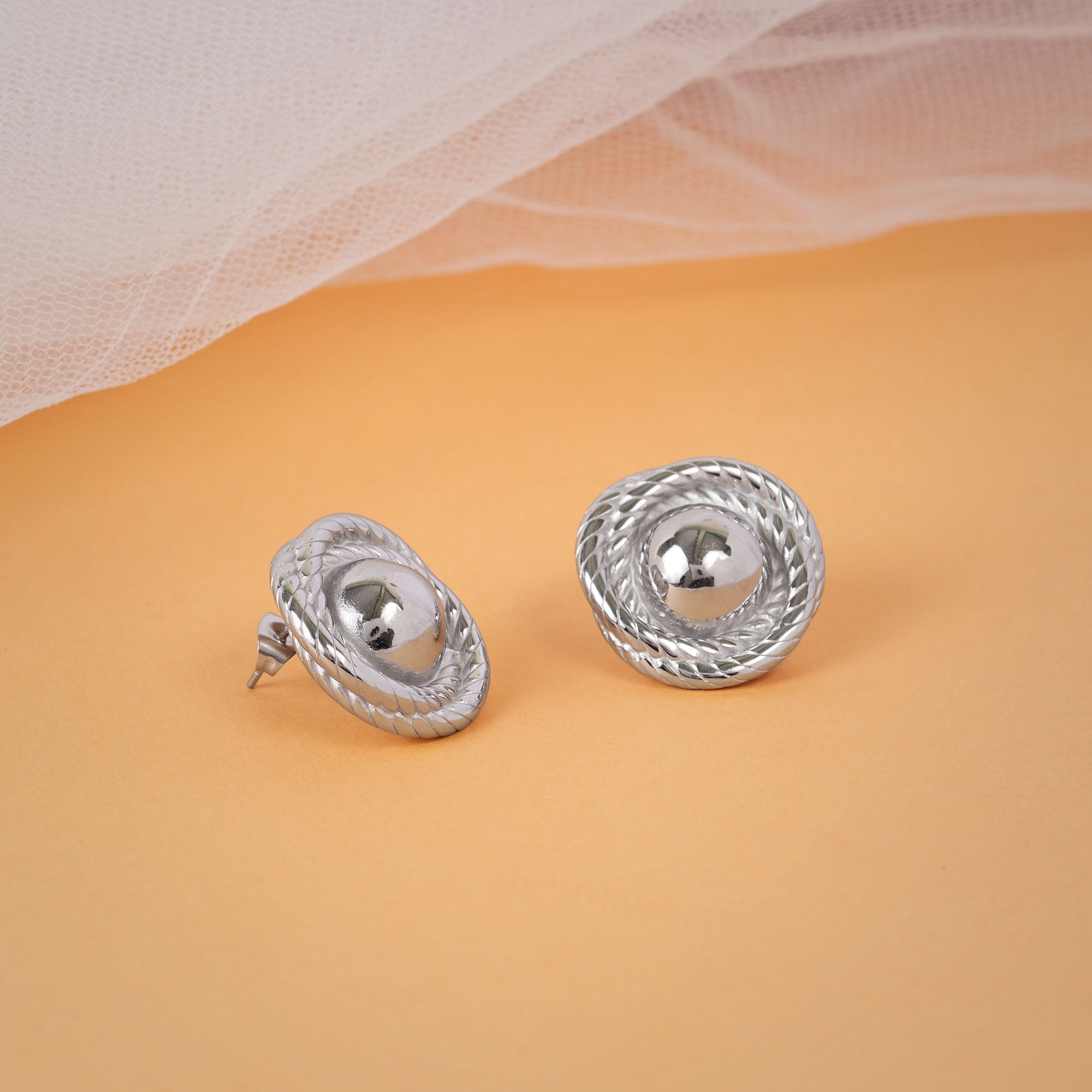 Pair of silver earrings on a beige background