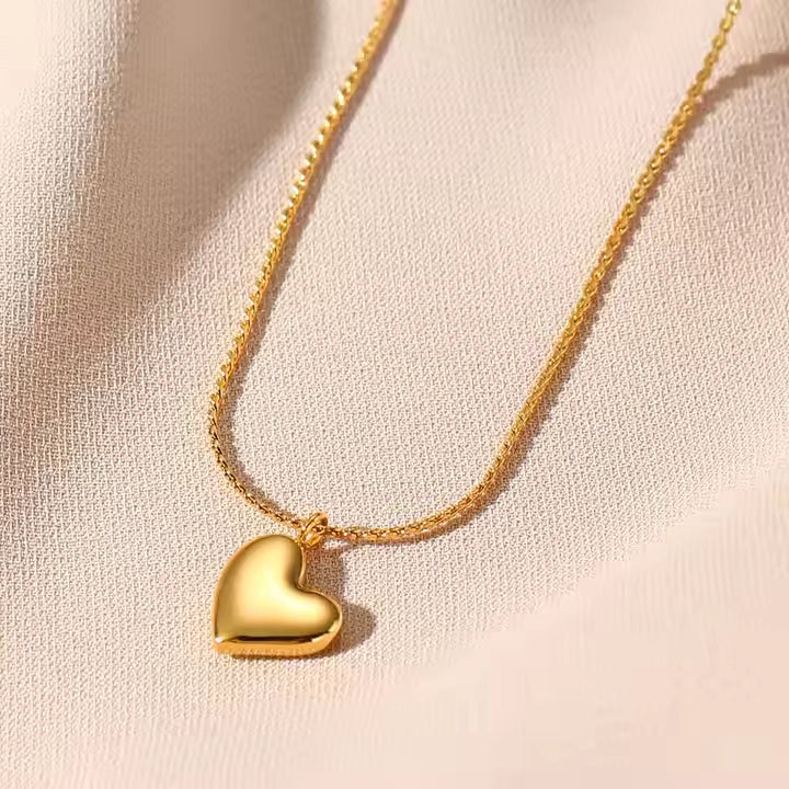 Gold heart-shaped pendant necklace on a beige fabric background