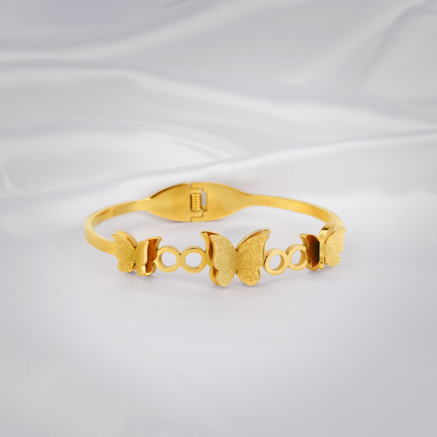 Gold bracelet with butterfly designs on a light gray background