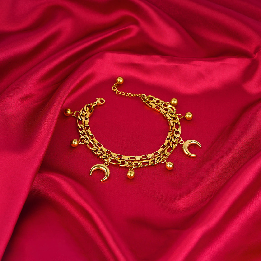 Gold bracelet with charms on a red satin background