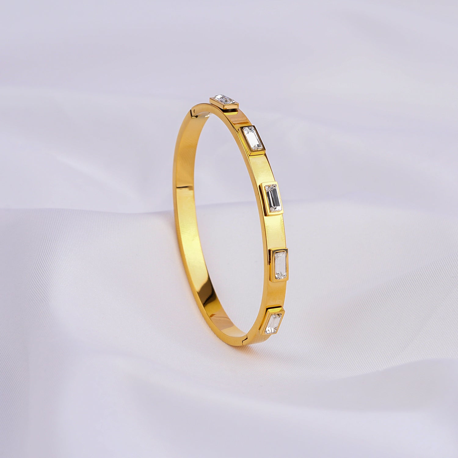 Gold bracelet with embedded stones on a light gray background