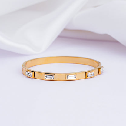 Gold bracelet with embedded crystals on a light fabric background