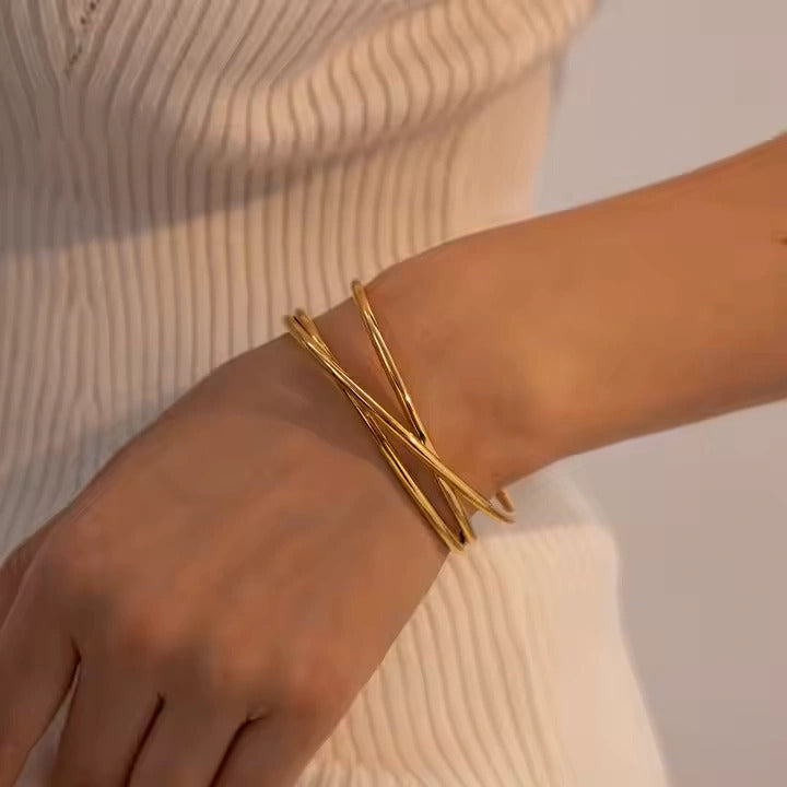 Gold bracelet on a wrist with a neutral background