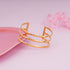 Gold bracelet on a pink surface with a soft pink background