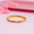 Gold beaded bracelet on a pink background