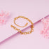 Gold chain bracelet on a pink background with floral elements