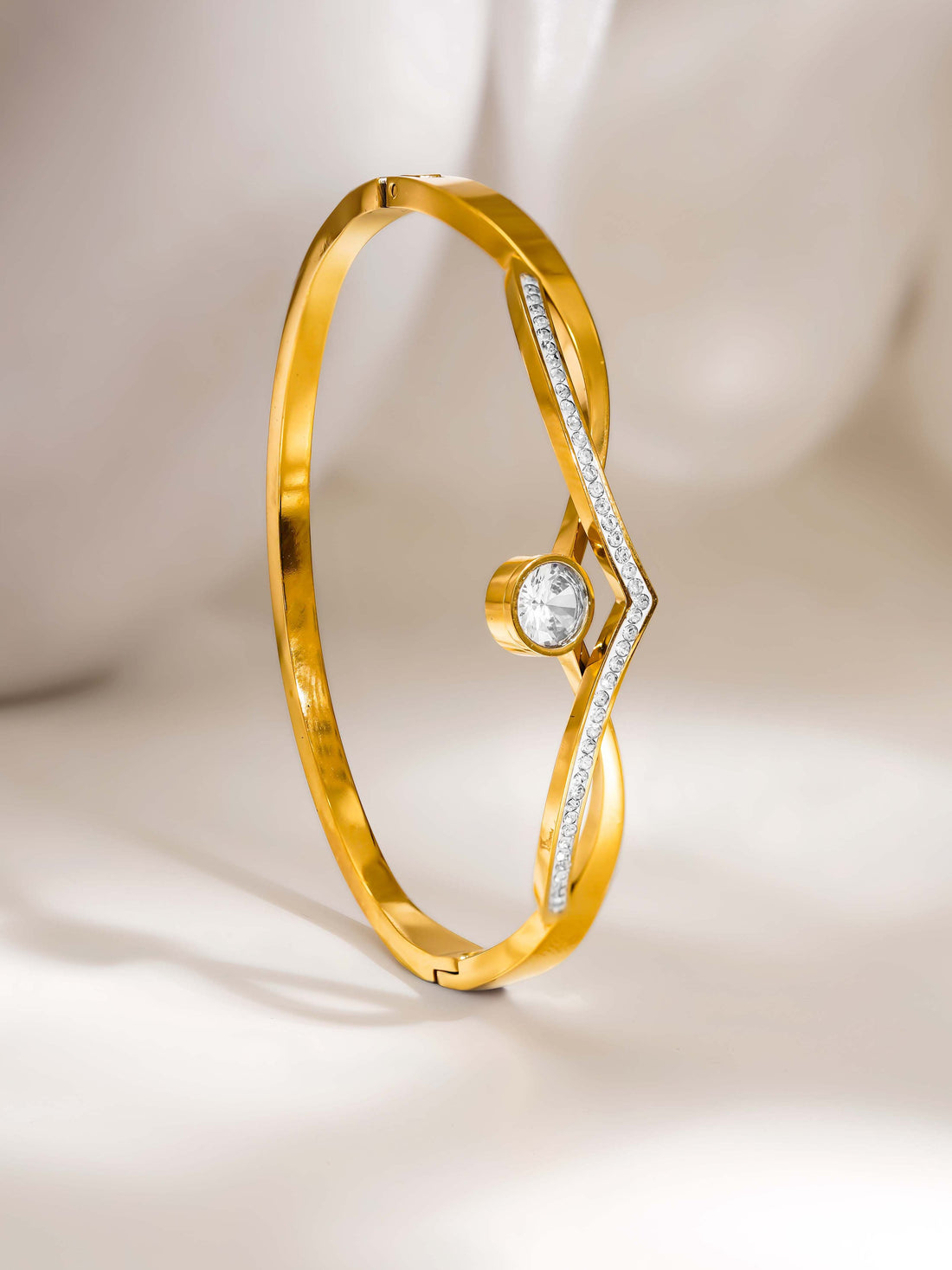 Gold bracelet with a diamond on a light beige background