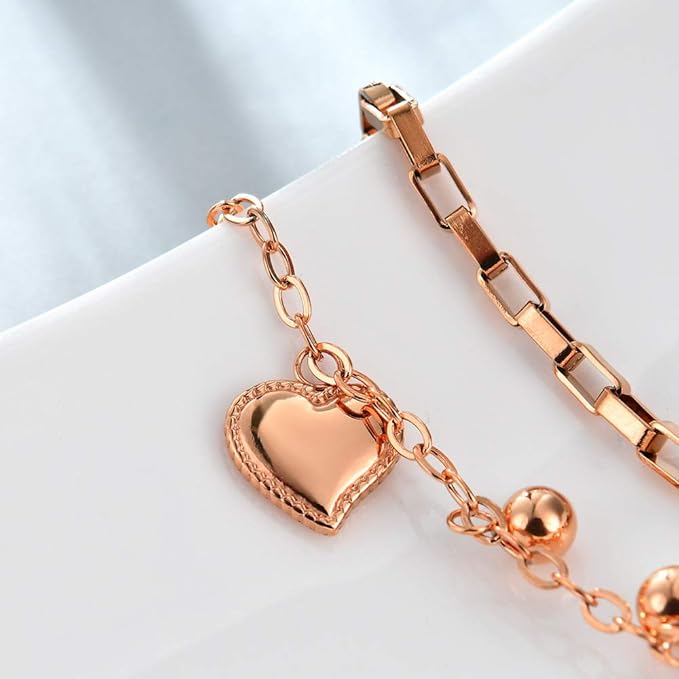 Rose gold bracelet with heart charm on a light background
