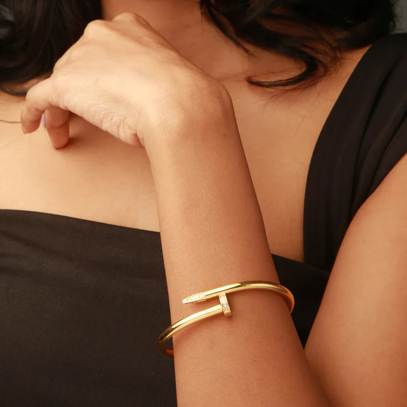 Close-up of a person wearing a gold bracelet on a blurred background