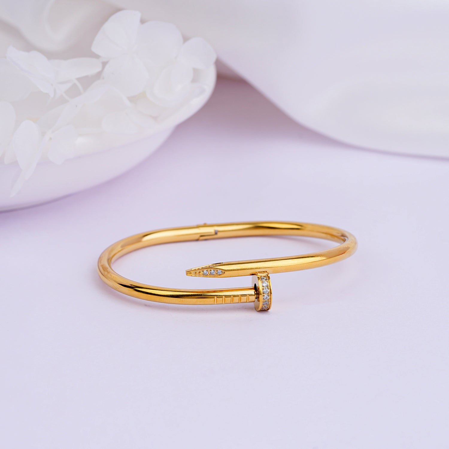 Gold nail bangle bracelet close-up on white background