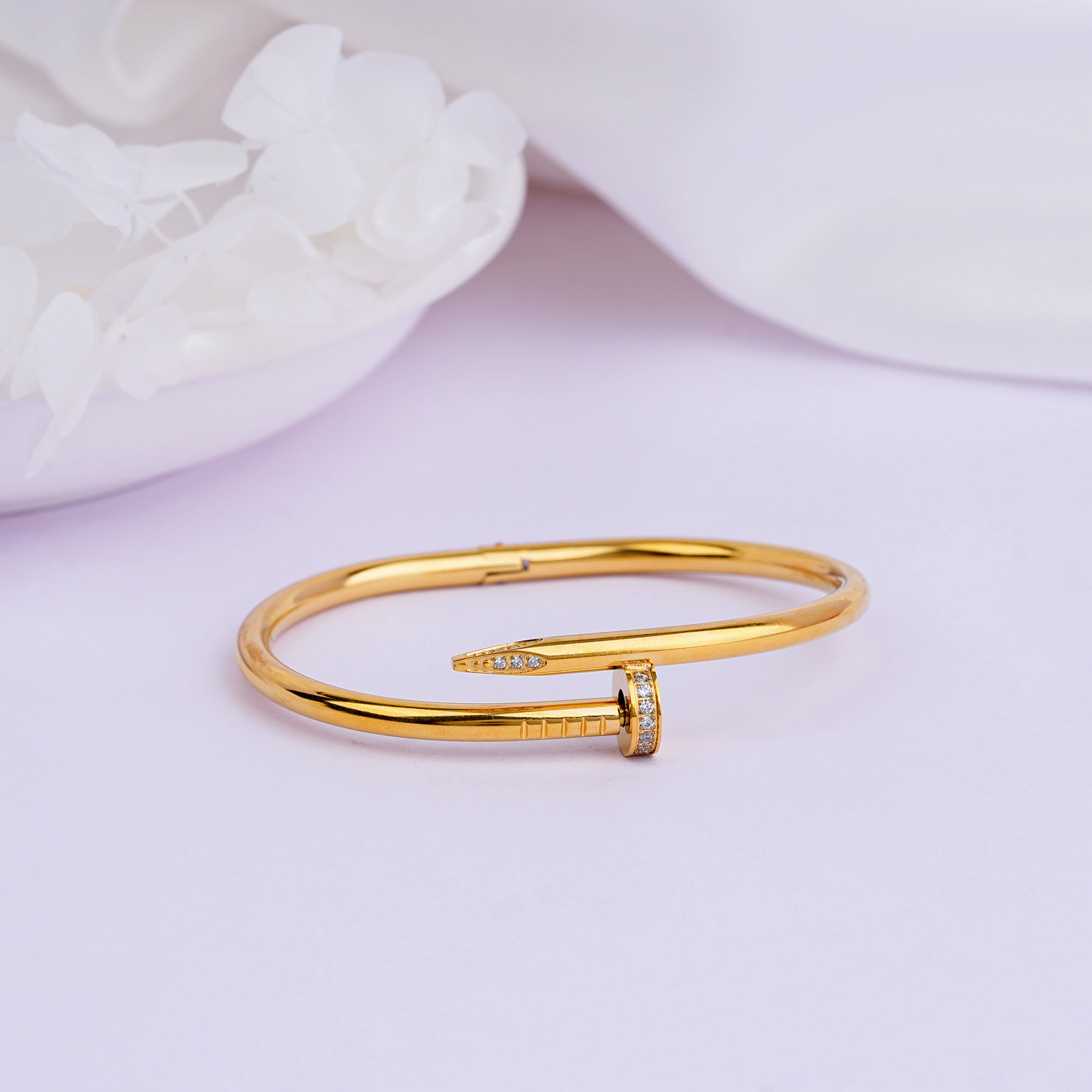 Gold nail bangle bracelet close-up on white background