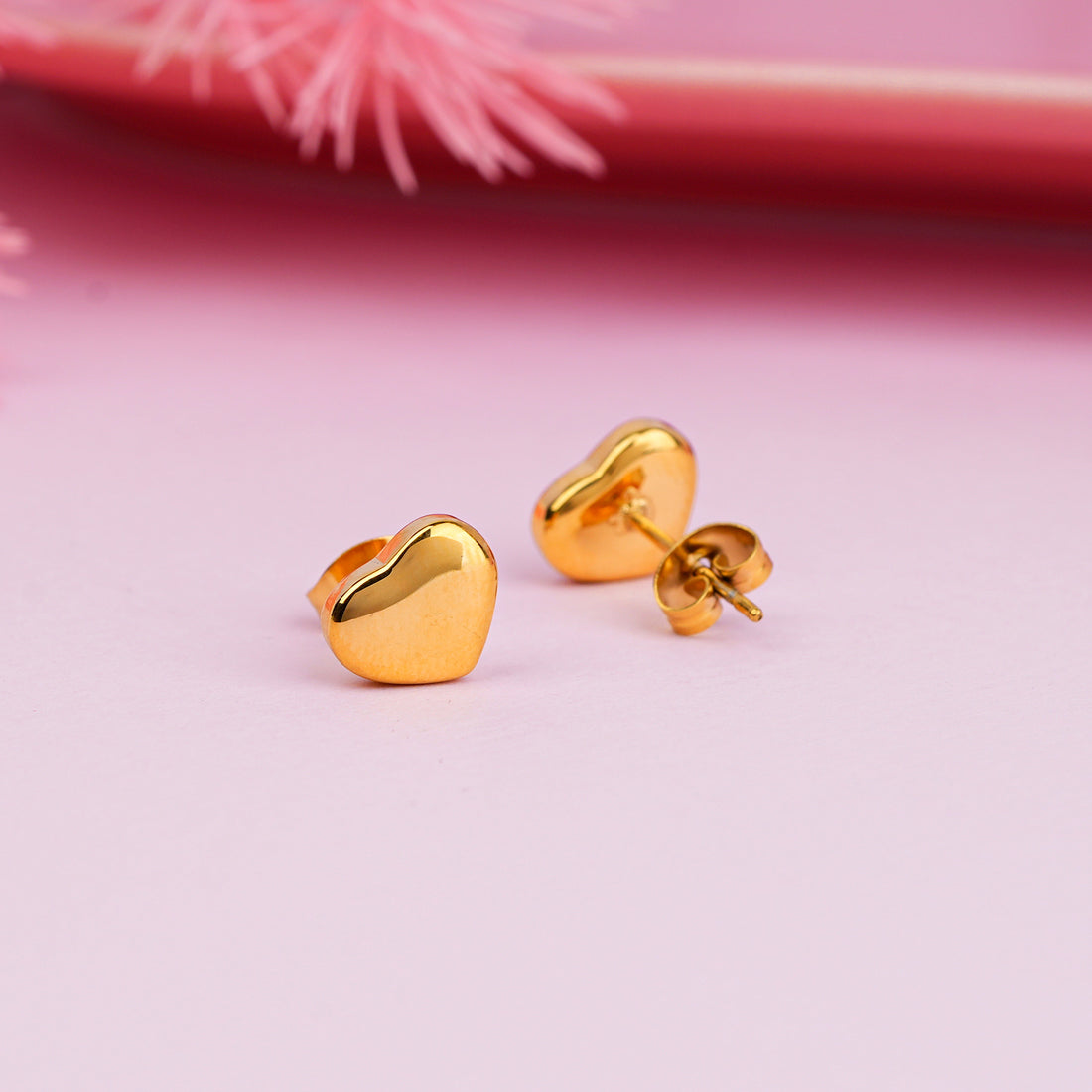 Glossy gold tiny heart stud earrings close-up