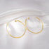 Gold hoop earrings on a white fabric background