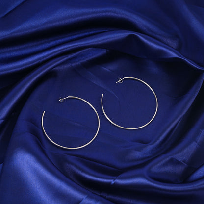 Gold hoop earrings on a blue satin fabric background