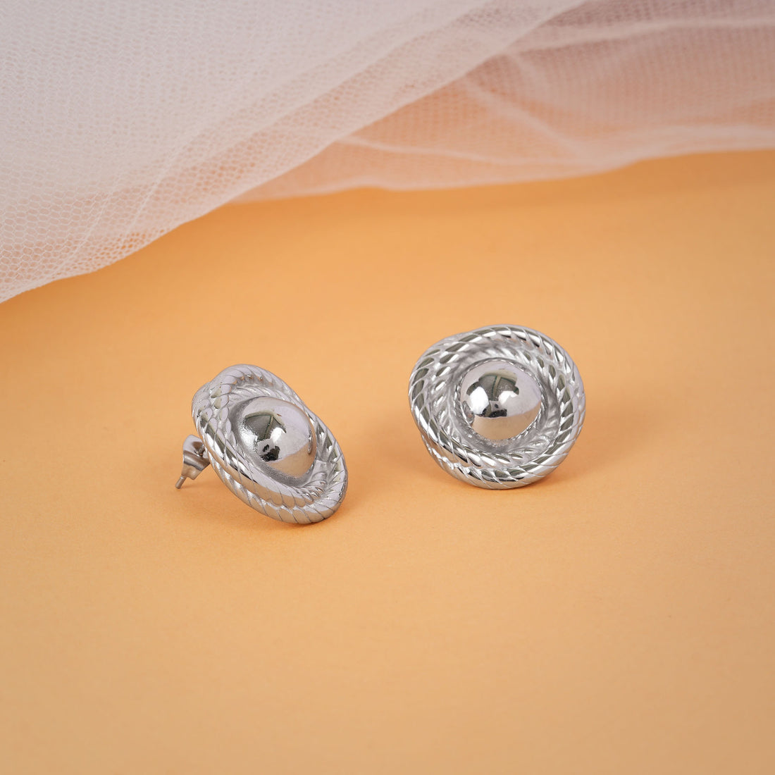 Pair of silver earrings on a beige background