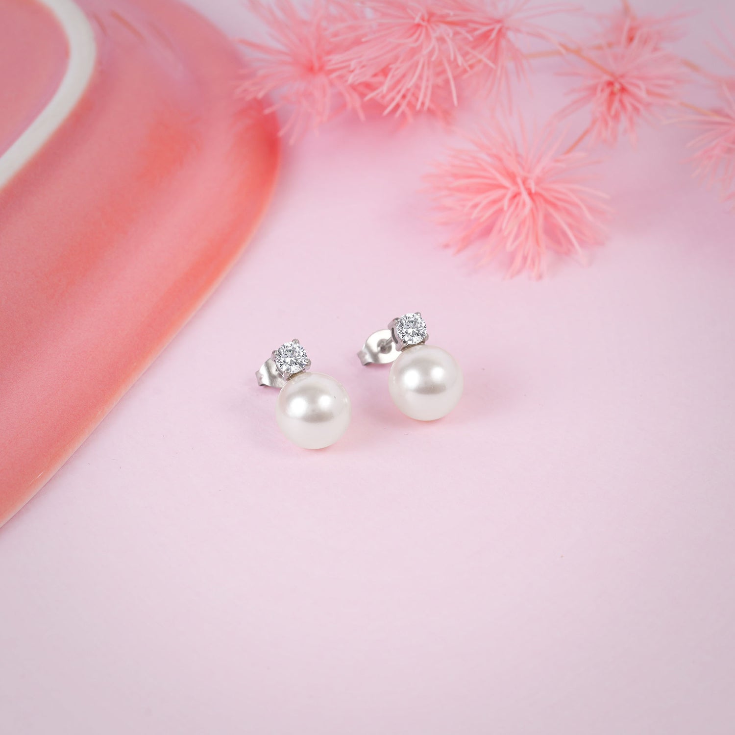 Pearl earrings with silver accents on a pink fabric background