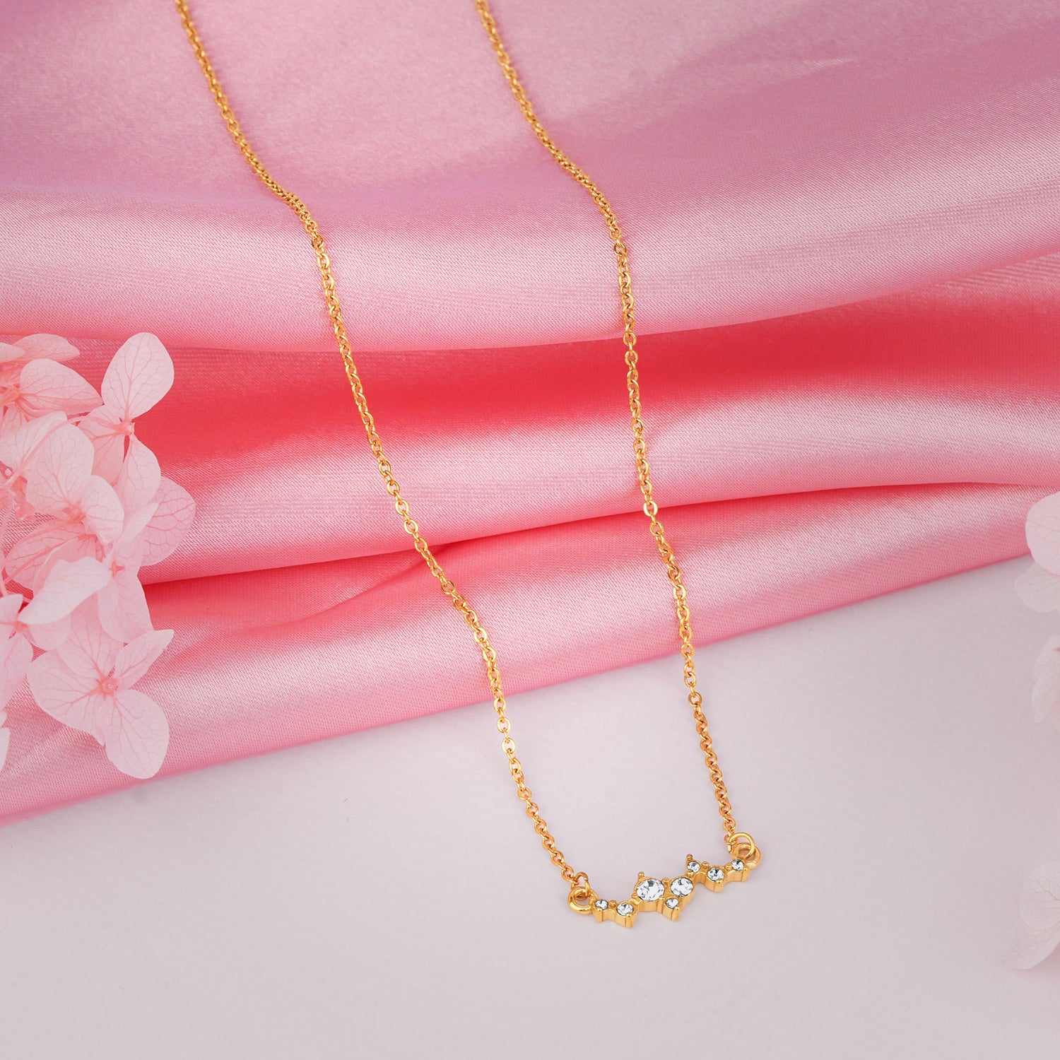 Gold necklace on a pink fabric background with flowers