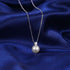 Pearl necklace with a silver chain on a blue fabric background