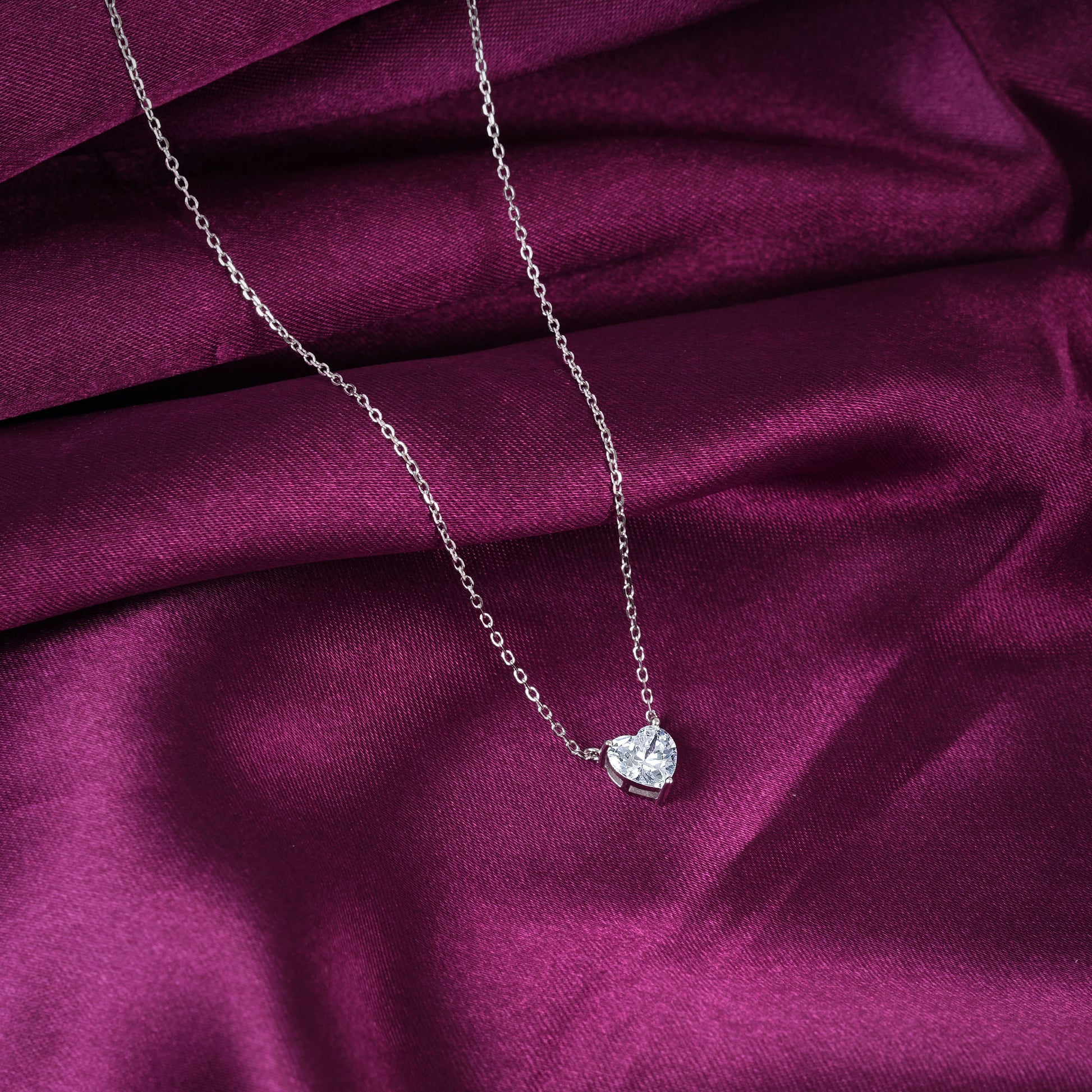 Heart-shaped diamond necklace on a purple fabric background