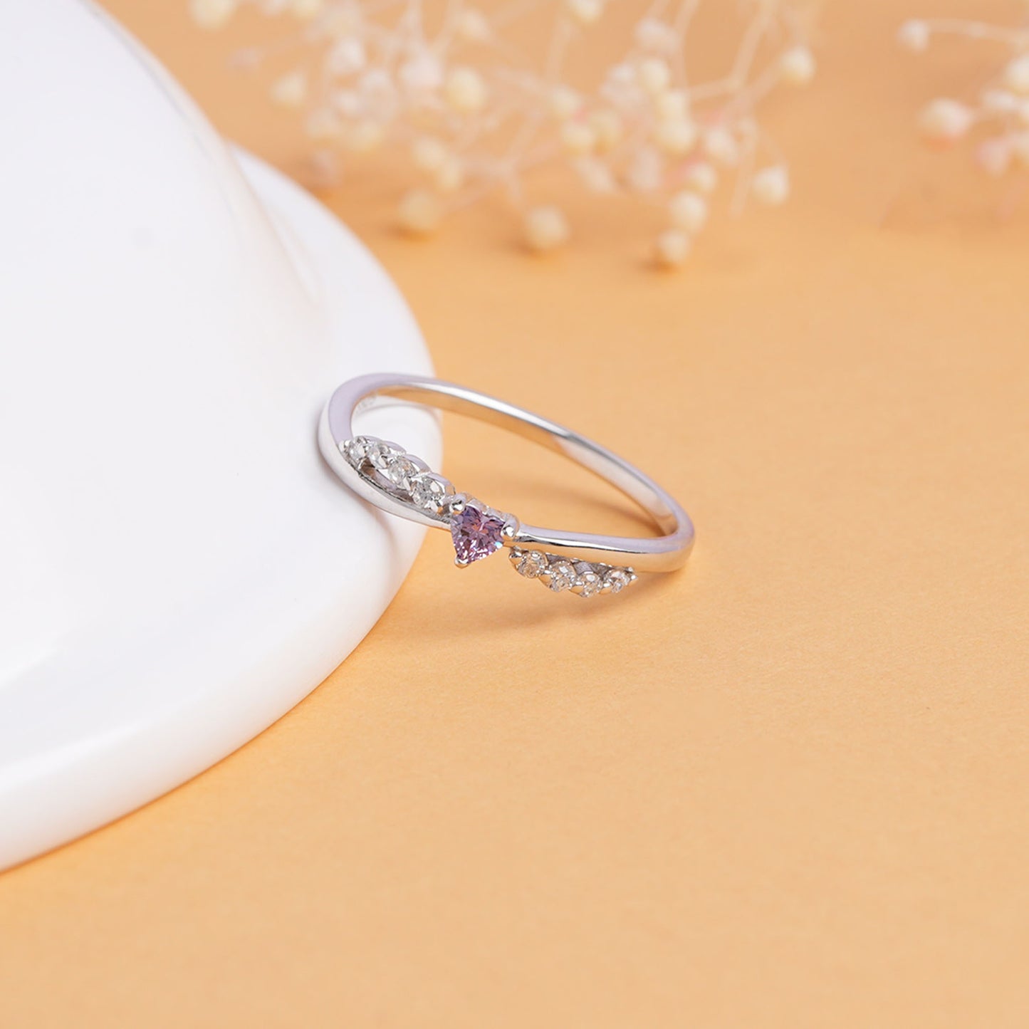 Silver ring with a purple gemstone on a beige background
